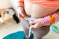 Woman measures her abdomen with a measuring tape