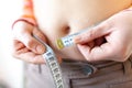 Woman measures her abdomen with a measuring tape