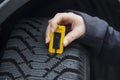 Woman measures tire tread of a car tire