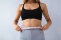Woman measuring her waist on light background, closeup. Weight loss concept, Young slim woman measuring her body with a tape me, Royalty Free Stock Photo