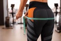 Woman measuring hips with tape in gym, closeup