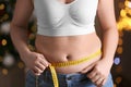Woman with measuring tape indoors, closeup. Overweight problem after New Year party