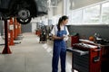 Woman mechanic choosing correct tool for car repair
