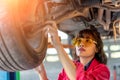 Woman Mechanic Examining Under the Car at the Repair Garage