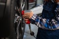 Woman mechanic uses pneumatic wrench to tighten the wheel nut. Girl at men& x27;s work. Royalty Free Stock Photo