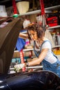 Woman mechanic with a wrench adjusts the car`s engine