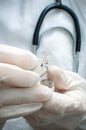 A woman medic in medical gloves opens a glass ampoule with the drug. Hands close-up, vertical. Selective focus