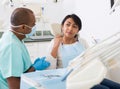 Woman in medical chair complains of toothache to dentist