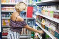 Woman with medical face mask doing one`s shopping in the market. Life during coronavirus time