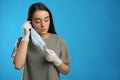 Woman in medical gloves putting on protective face mask against blue background. Space for text Royalty Free Stock Photo