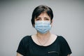 Woman in Medical Mask. Breathes deeply and looking at camera on grey background outdoor. Health care and medical concept Royalty Free Stock Photo
