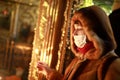 Woman in medical mask with candle in church