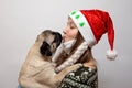 Woman in medical mask and Christmas hat kissing with pug dog. Coronavirus and Christmas Royalty Free Stock Photo