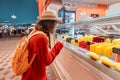 Woman in a medical mask during the covid-19 outbreak walks in the park and chooses a delicious ice cream in the refrigerator in