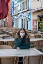 Woman with medical mask in empty cafe terrace