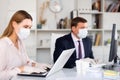 Woman in medical mask and gloves working on laptop in office