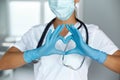 Woman with a medical mask and hands in latex glove shows the symbol of the heart. Doctor for the heart Royalty Free Stock Photo