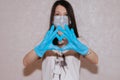 Woman with a medical mask and hands in latex glove shows the symbol of the heart. Doctor for the heart. Love to our Royalty Free Stock Photo