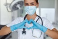 Woman with a medical mask and hands in latex glove shows the symbol of the heart. Doctor for the heart. Royalty Free Stock Photo