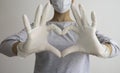 Woman with a medical mask and hands in latex white gloves shows the symbol of the heart. Doctor for the heart. Royalty Free Stock Photo
