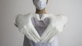 Woman with a medical mask and hands in latex white sterile latex surgical gloves shows the symbol of the heart Royalty Free Stock Photo