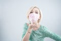 Woman in a medical mask send kiss. Young caucasian female in pink face mask wearing party dress and urges everyone to take care of