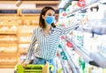 Woman in medical mask shopping in supermarket taking milk Royalty Free Stock Photo