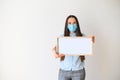 Woman in a medical mask stands with a blank board