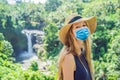 Woman in medical mask traveler on a waterfall background. Ecotourism concept Tourists fear the 2019-ncov virus. Medical