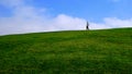 Woman with medical mask walking on a green hillside under blue sky Royalty Free Stock Photo