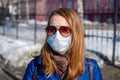 A woman in a medical mask walks alone on the street during the quarantine. Portrait of a female in a protective face mask against
