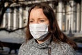 A woman in a medical mask walks alone on the street during the quarantine. Portrait of a female in a protective face mask against