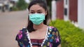 Woman in medical masksurgical mask walking outdside a home, coronavirus protection