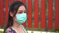 Woman in medical masksurgical mask walking outdside a home, coronavirus protection