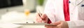 Woman medicine doctor with silver pen writes on a clipboard closeup.