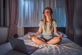 Woman meditates on bed using meditation app. sport, technology and healthy lifestyle concept