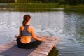 A woman meditates in nature by the lake. The concept of realizing the meaning of life