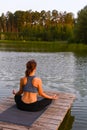 A woman meditates in nature by the lake. The concept of realizing the meaning of life