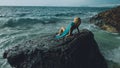 Woman meditates, relaxes on a rock reef hill in stormy morning rain cloudy sea. Concept feminine, relax, sexual health Royalty Free Stock Photo
