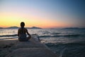 Woman meditates - relaxes at sunset by the sea on the beach. Concept for yoga, health and spa