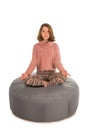 Woman meditates while sitting in the lotus position on round shape grey beanbag chair