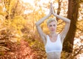 Woman meditating against blurry forest