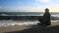 The woman is meditating on the beach during a storm. Equanimity, resistance to stress