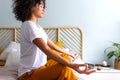 Woman meditating and breathing yoga exercises to calm mind. African American woman does meditation in bedroom. Royalty Free Stock Photo