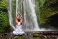 Woman meditating doing yoga between waterfalls Royalty Free Stock Photo