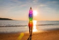 Woman is meditating with glowing seven chakras on the beach. Silhouette of woman is practicing yoga at sunset