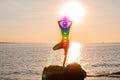 Woman is meditating with glowing seven chakras on the beach. Silhouette of woman is practicing yoga at sunset