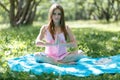 Woman meditating on green grass at the park sitting in lotus position. Fitness girl relaxing in yoga pose after exercises Royalty Free Stock Photo