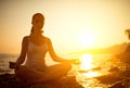 Woman meditating in lotus pose on the beach