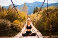 Woman meditating in lotus position on bridge over mountain river in forest Royalty Free Stock Photo